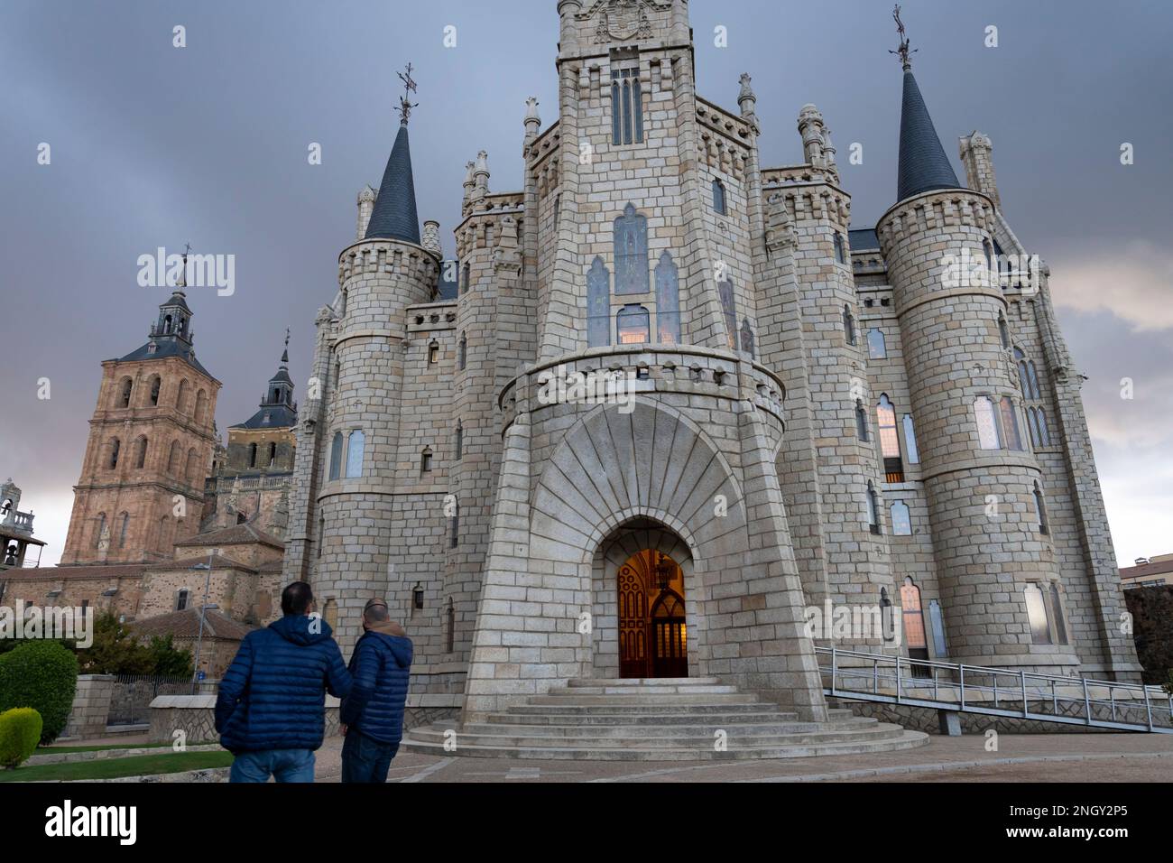 Der Eingang wird von einem warmen Licht erhellt, wenn sich im Episkopalpalast in Astorga, Leon, Spanien Sturmwolken sammeln. Das Wahrzeichen Gebäude von Katalanisch ar Stockfoto