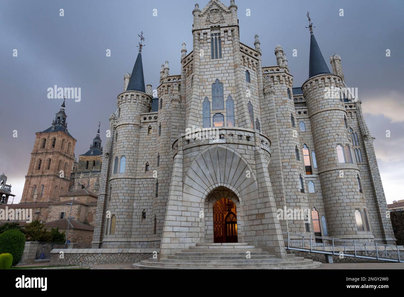 Der Eingang wird von einem warmen Licht erhellt, wenn sich im Episkopalpalast in Astorga, Leon, Spanien Sturmwolken sammeln. Das Wahrzeichen Gebäude von Katalanisch ar Stockfoto