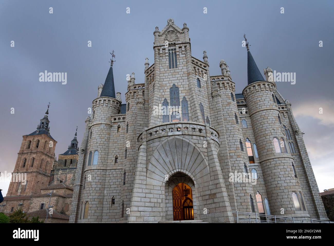Der Eingang wird von einem warmen Licht erhellt, wenn sich im Episkopalpalast in Astorga, Leon, Spanien Sturmwolken sammeln. Das Wahrzeichen Gebäude von Katalanisch ar Stockfoto