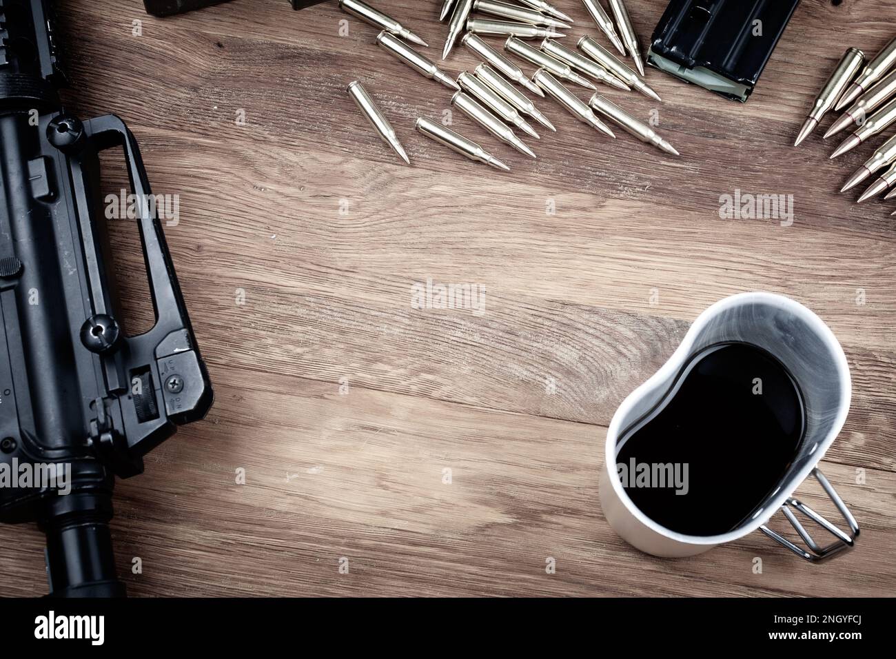 Schwarzes Gewehr und schwarzer Kaffee. Sturmgewehr und Tasse Kaffee auf Holztisch-Hintergrund. Stockfoto