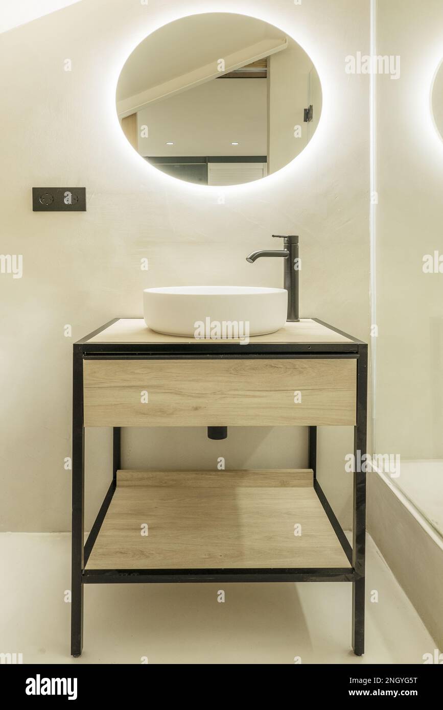 Badezimmer mit Waschbecken im Industriestil aus Holz und Eisen mit rundem Spiegel Stockfoto