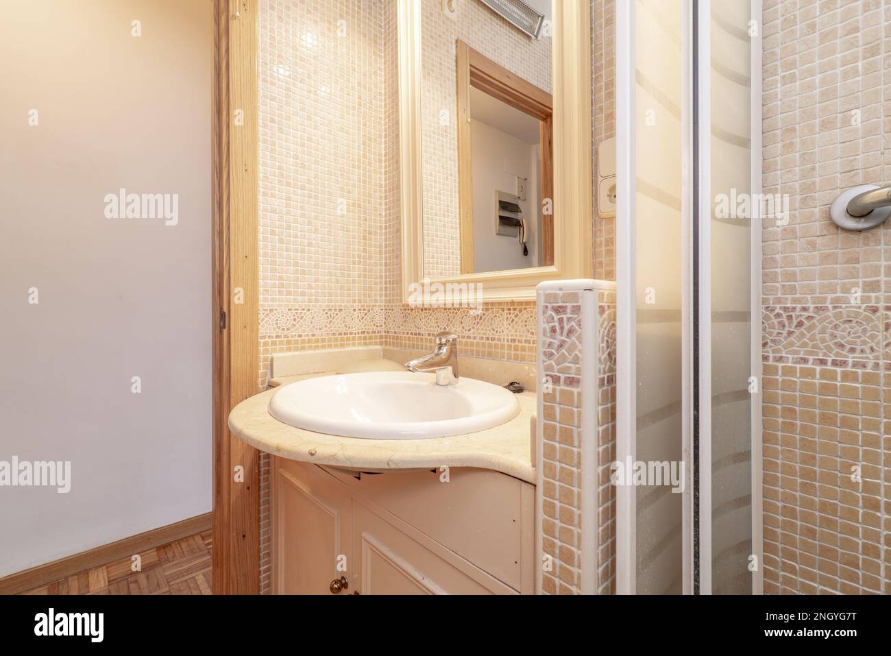 Badezimmer mit cremefarbener Marmorplatte und Spiegel mit Holzrahmen und Duschschale mit Fliesen und Türrahmen aus Eichenholz Stockfoto