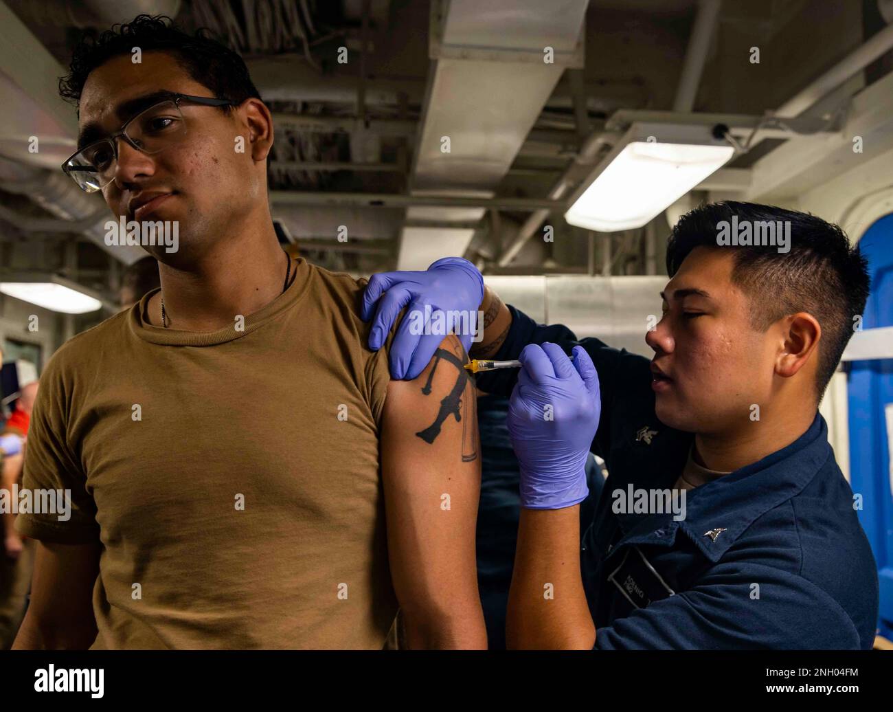 221202-N-XK047-2003 PAZIFIK (2. Dez. 2022) – Hospital Corpsman 2. Klasse Koenig Tan verabreicht eine Typhusimpfung an Gunner's Mate 2. Klasse Eugenio Gonzalez an Bord des Amphibienschiffes USS Makin Island (LHD 8), 2. Dez. 2022. Typhus-Impfungen können Typhus verhindern, eine lebensbedrohliche Krankheit, die in vielen Regionen der Welt verbreitet ist und Symptome wie anhaltendes hohes Fieber, Schwäche, Bauchschmerzen und Appetitlosigkeit beinhaltet. Makin Island Amphibious Ready Group, bestehend aus dem Amphibienschiff USS Makin Island (LHD 8) und dem Amphibiendock USS Anch Stockfoto