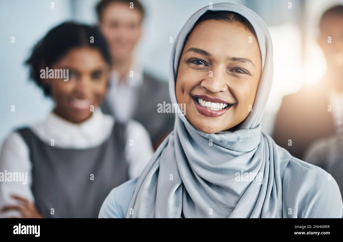 Lächeln ist ein langer Weg. Porträt einer selbstbewussten jungen Geschäftsfrau, die im Büro bei der Arbeit steht. Stockfoto