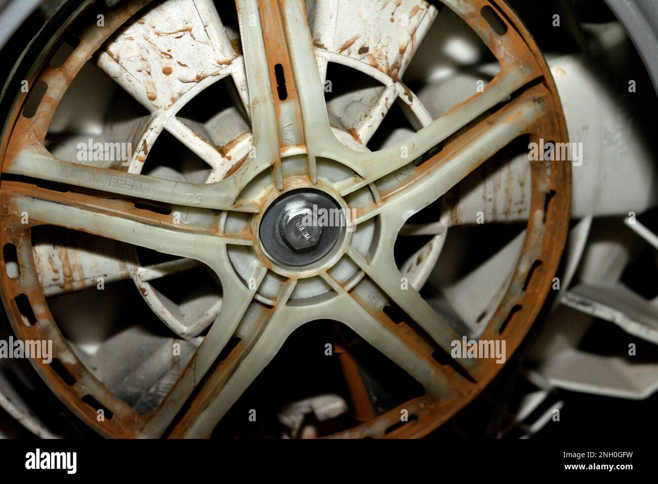 Rostige alte, schmutzige Trommel der automatischen elektrischen Waschmaschine, die mit dem Motor der Maschine verbunden ist, Wartung der Waschmaschine, Befestigung der Maschine und Stockfoto