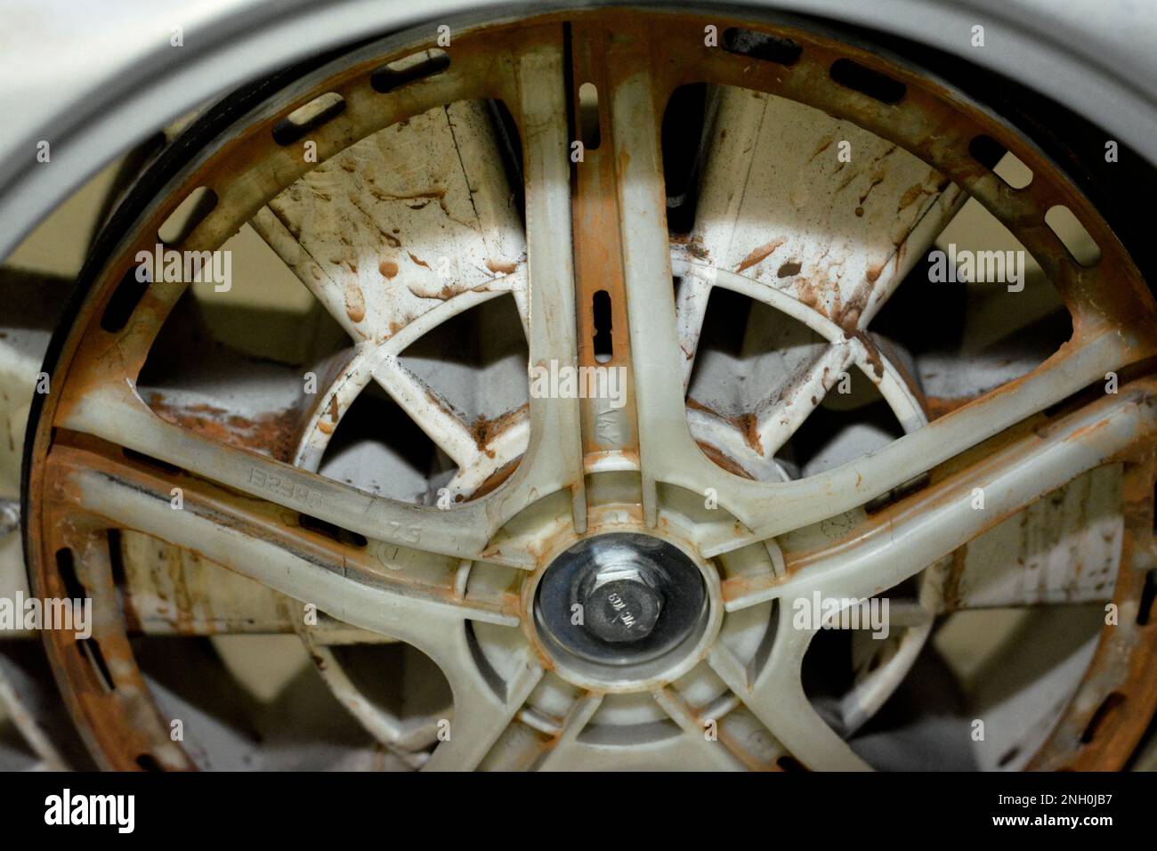 Rostige alte, schmutzige Trommel der automatischen elektrischen Waschmaschine, die mit dem Motor der Maschine verbunden ist, Wartung der Waschmaschine, Befestigung der Maschine und Stockfoto