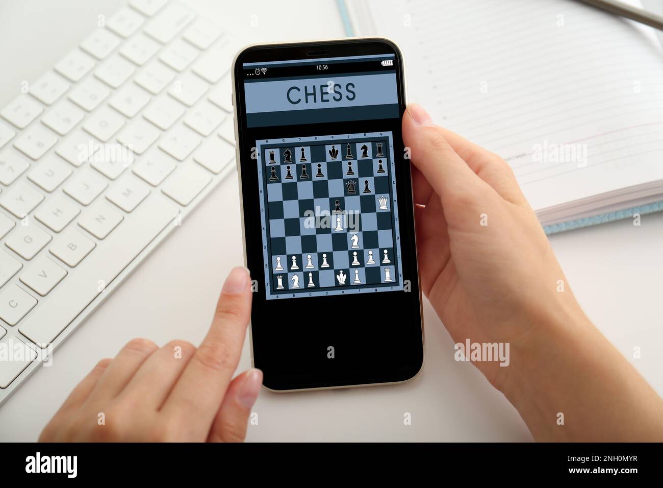 Frau, die online Schach auf einem Smartphone spielt, am Tisch, Nahaufnahme Stockfoto