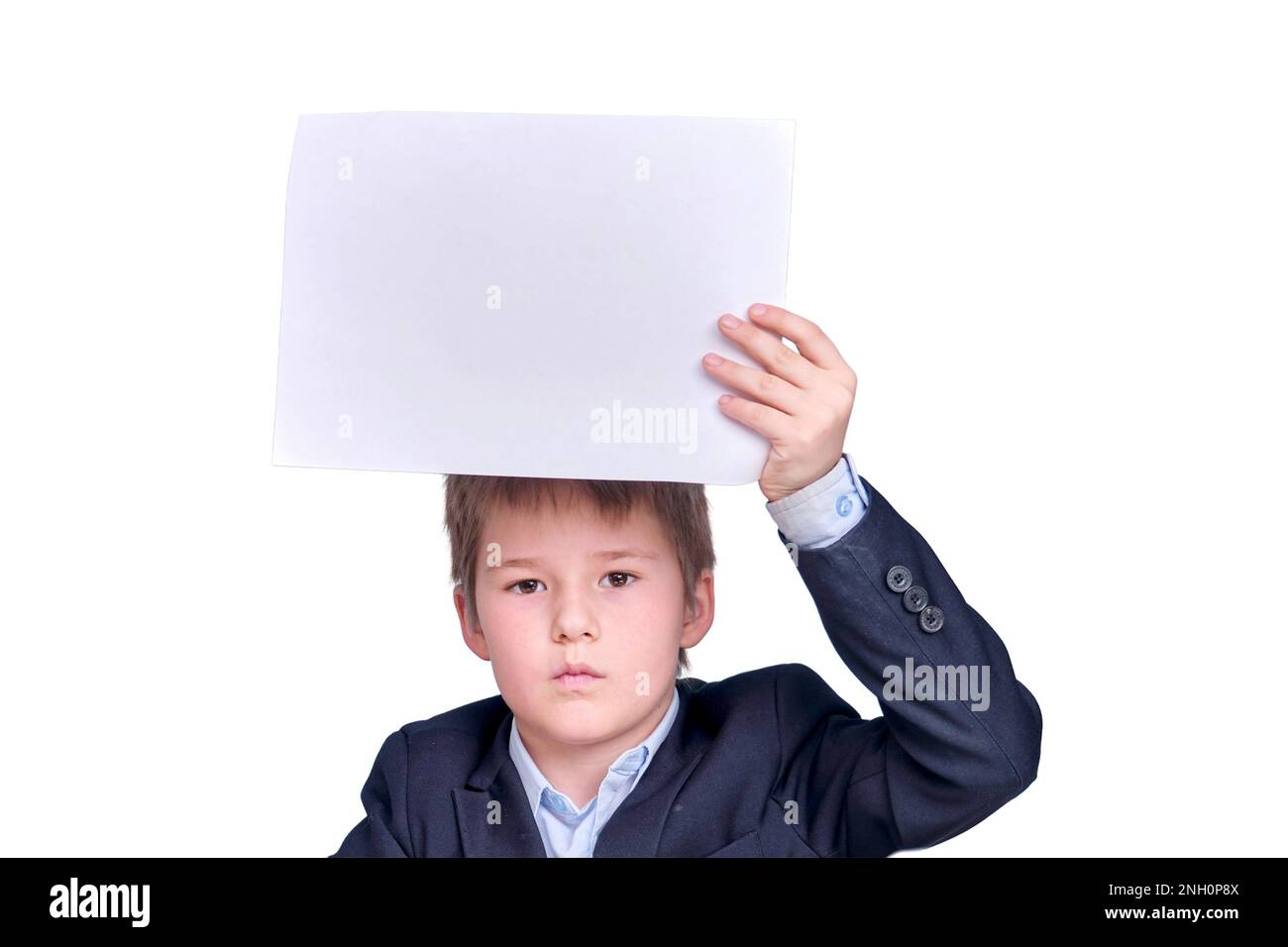 Ein Junge im Schulanzug mit einem Blatt A4-Papier während des Fernunterrichts, isoliert auf weißem Hintergrund Stockfoto