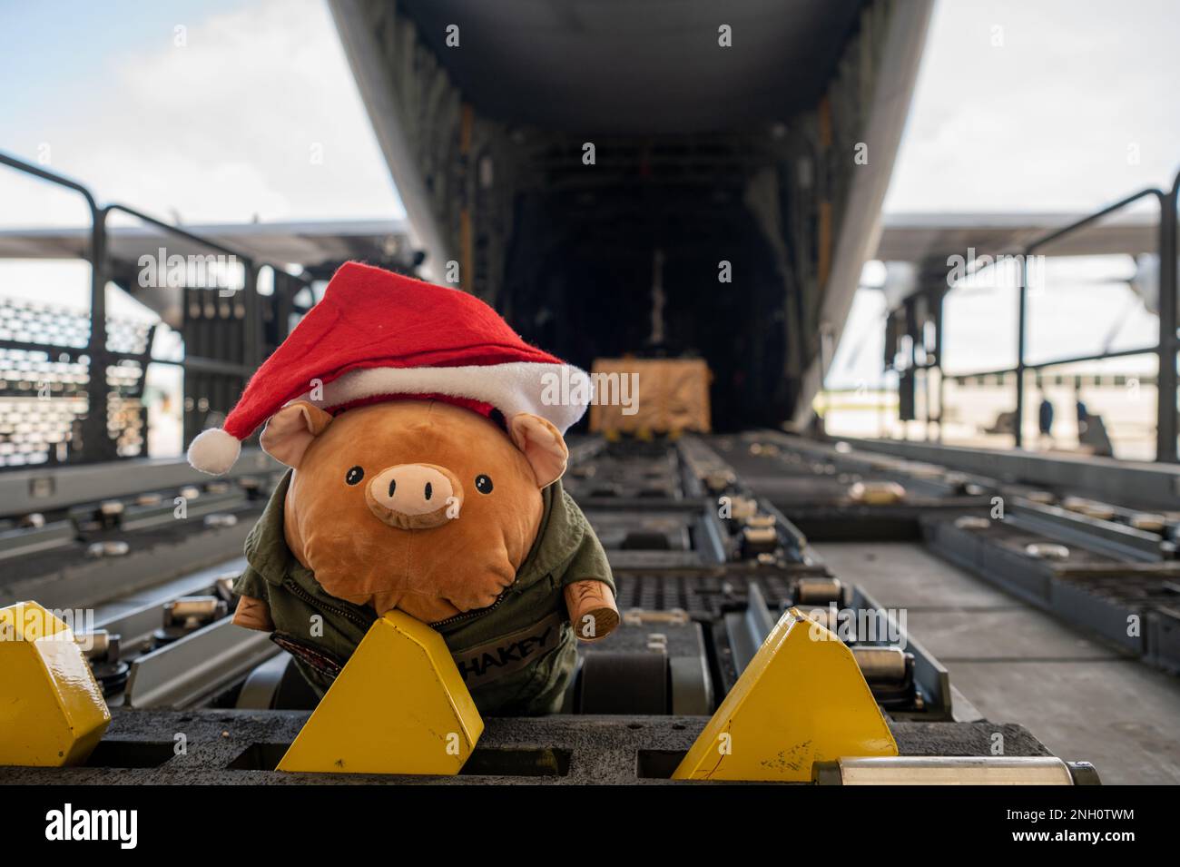 Shakey, das Schwein, sitzt vor einem C-130J Super Hercules während der Push-Zeremonie für die 71. Iteration von Operation Christmas Drop auf dem Luftwaffenstützpunkt Andersen am 5. Dezember 2022. Operation Christmas Drop 2022 wird 200 Tropfen gespendeter Güter per Lufttransport an 56 Inseln im Pazifik liefern, von denen mehr als 23.000 Menschen betroffen sind. Stockfoto