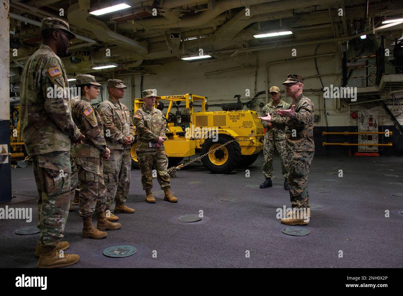 SAN DIEGO (5. DEZEMBER 2022) USA Rod McDaniel, Chief Warrant Officer des Marine Corps, stammt aus Raceland, Kentucky, erklärt die Integration von Navy und Marine Corps an Bord der USS Boxer (LHD 4) mit Soldaten der Public Health Activity-San Diego während einer Einführungstour des Schiffs auf dem oberen Fahrzeugdeck. Die Public Health Command-Pacific Public Health Activity in San Diego stellt Lebensmittelinspektoren für Schiffe zur Verfügung, die auf dem Marinestützpunkt San Diego Homeportiert sind, darunter Boxer, ein Amphibienschiff der Wasp-Klasse. Stockfoto