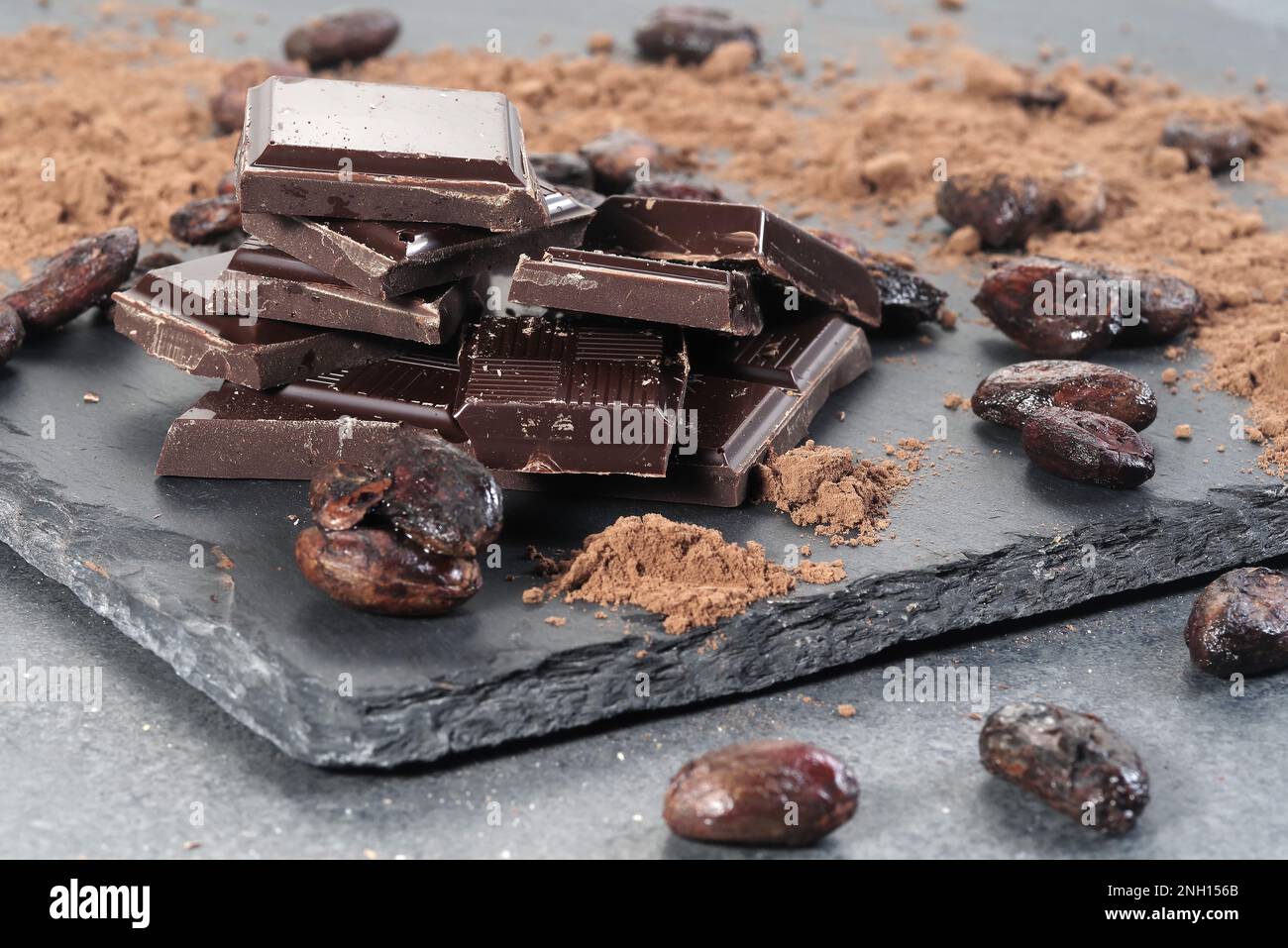 Zerbrochene dunkle Schokolade und Kakaobohnen auf einem Tisch Stockfoto