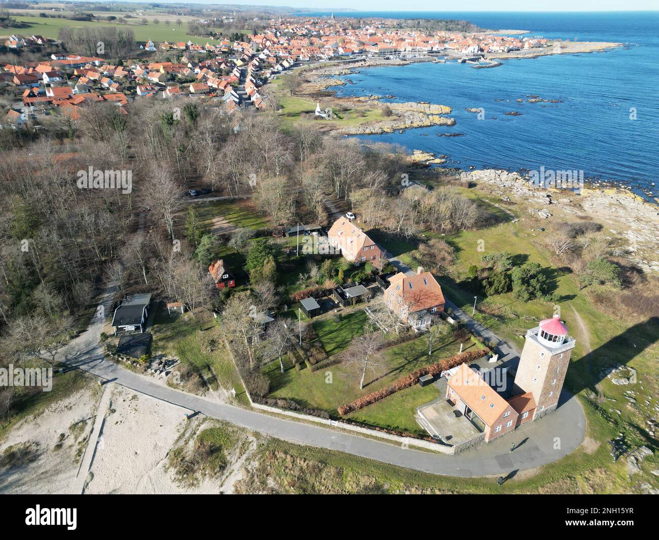 Ein malerisches Dorf in der Nähe einer ruhigen Küste mit einem Leuchtturm und einem gewundenen Pfad zum Strand Stockfoto