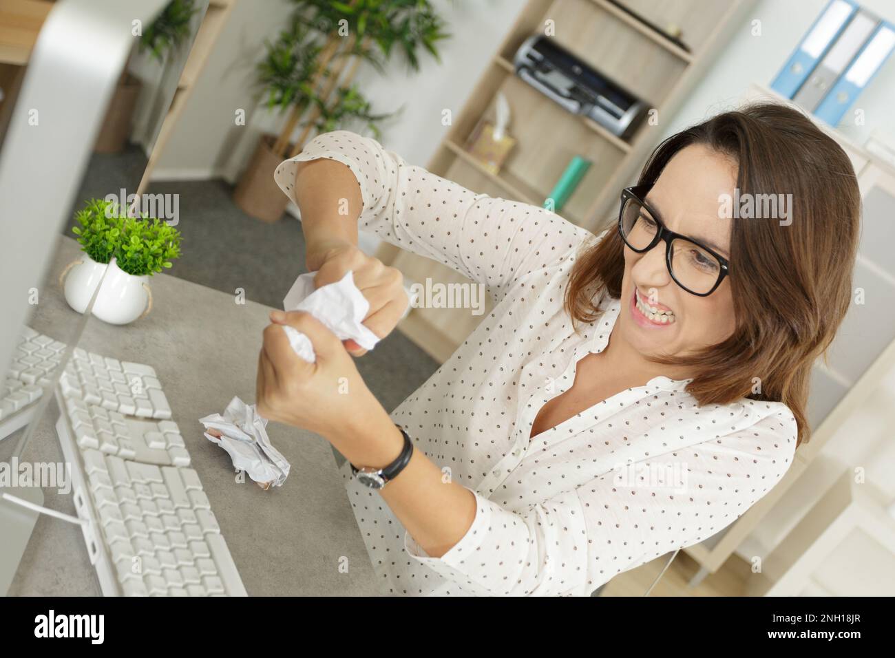 Frau, die Computer benutzt und Papier vermasselt hat, in Wut Stockfoto