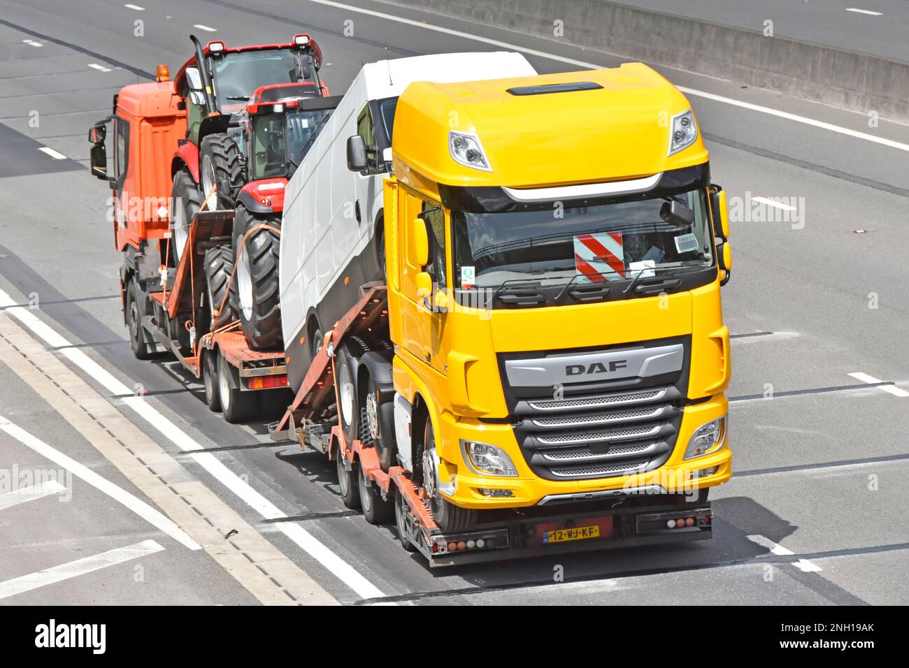 Low-Loader-Lkw und -Anhänger mit einstellbaren Tragböcken für neue Nutzfahrzeuge Landwirtschaftstraktoren, weißer Lieferwagen und gelber DAF-lkw-Lkw auf der britischen Autobahn Stockfoto