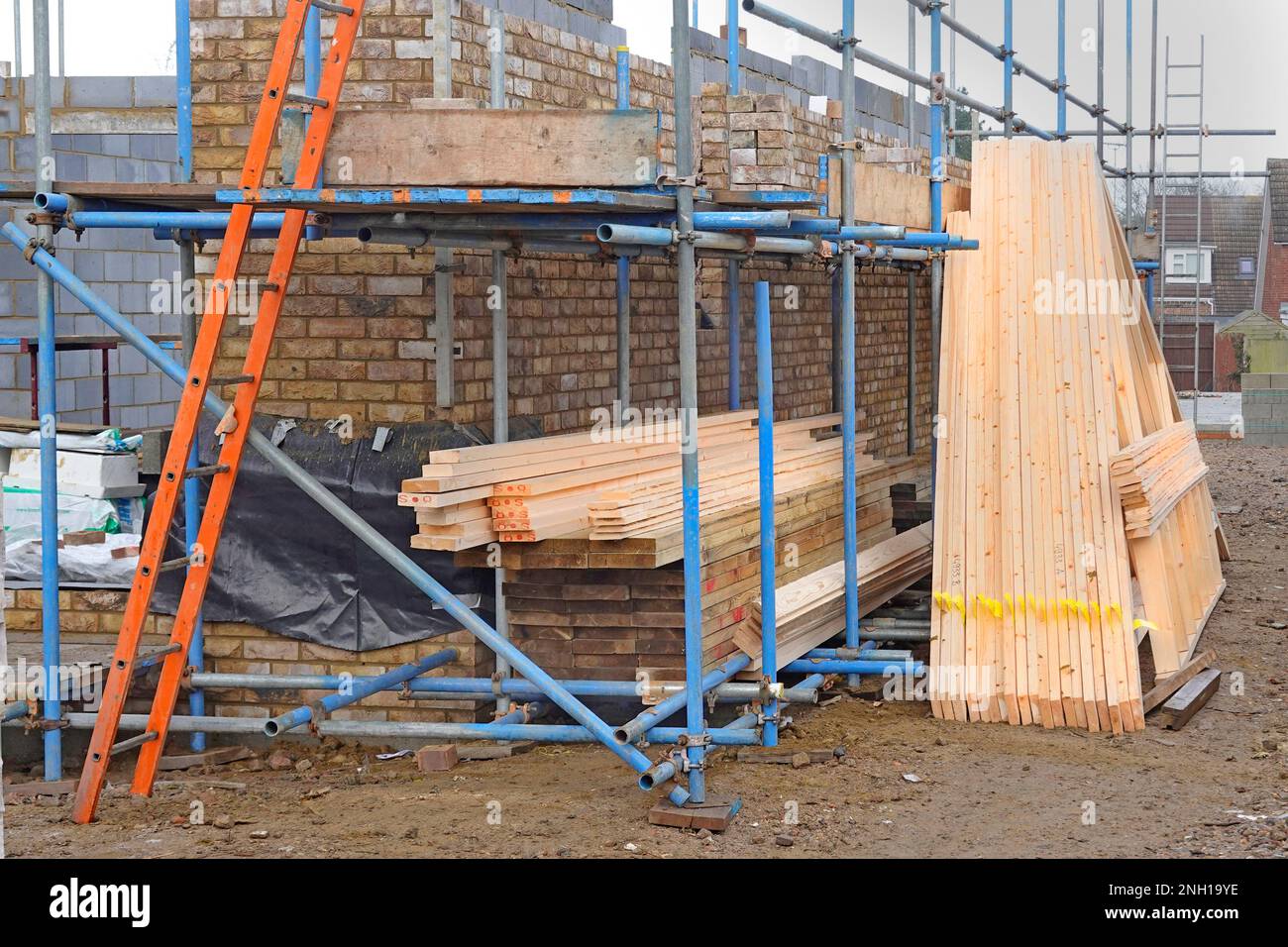 Werkseitig vorgefertigte und chemisch behandelte Dachträger aus Holz werden mit Holzbodenträgern geliefert, die für den Bau in das neue Haus in Großbritannien bereit gelagert werden Stockfoto