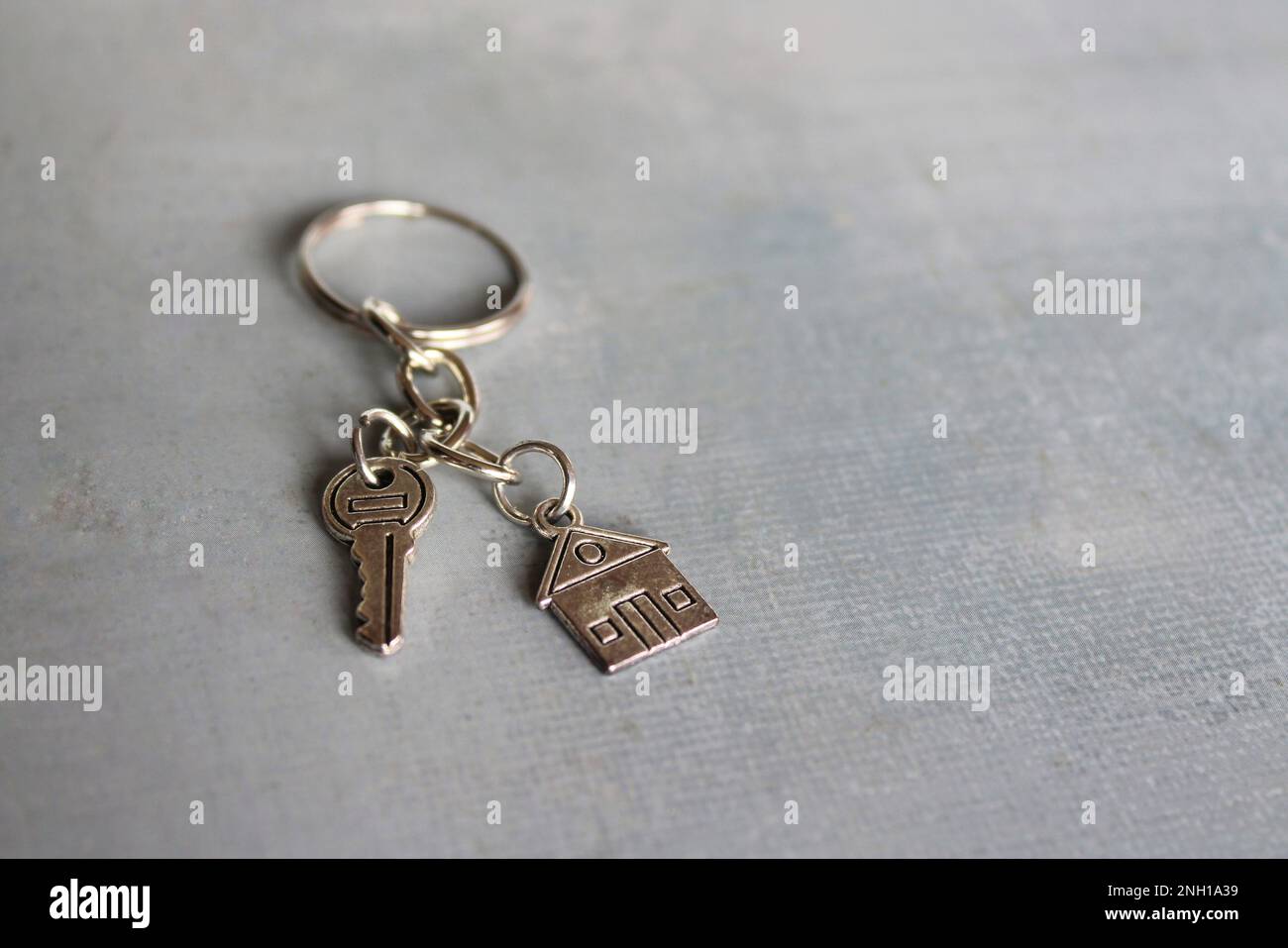 Nahaufnahme eines hausförmigen Schlüsselbands und Schlüssels mit Kopierbereich. Hausbesitzkonzept. Stockfoto
