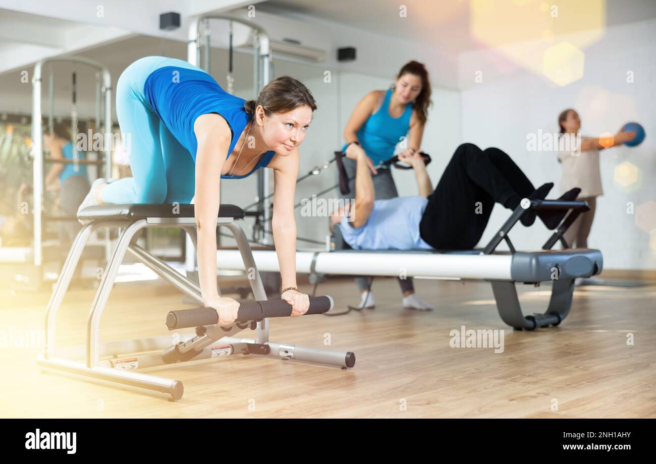 Lachelnde Frau mittleren Alters die Pilates System auf Wanda Stuhlmaschine im Studio praktiziert um die Beweglichkeit des Korpers zu verbessern Stockfotografie Alamy