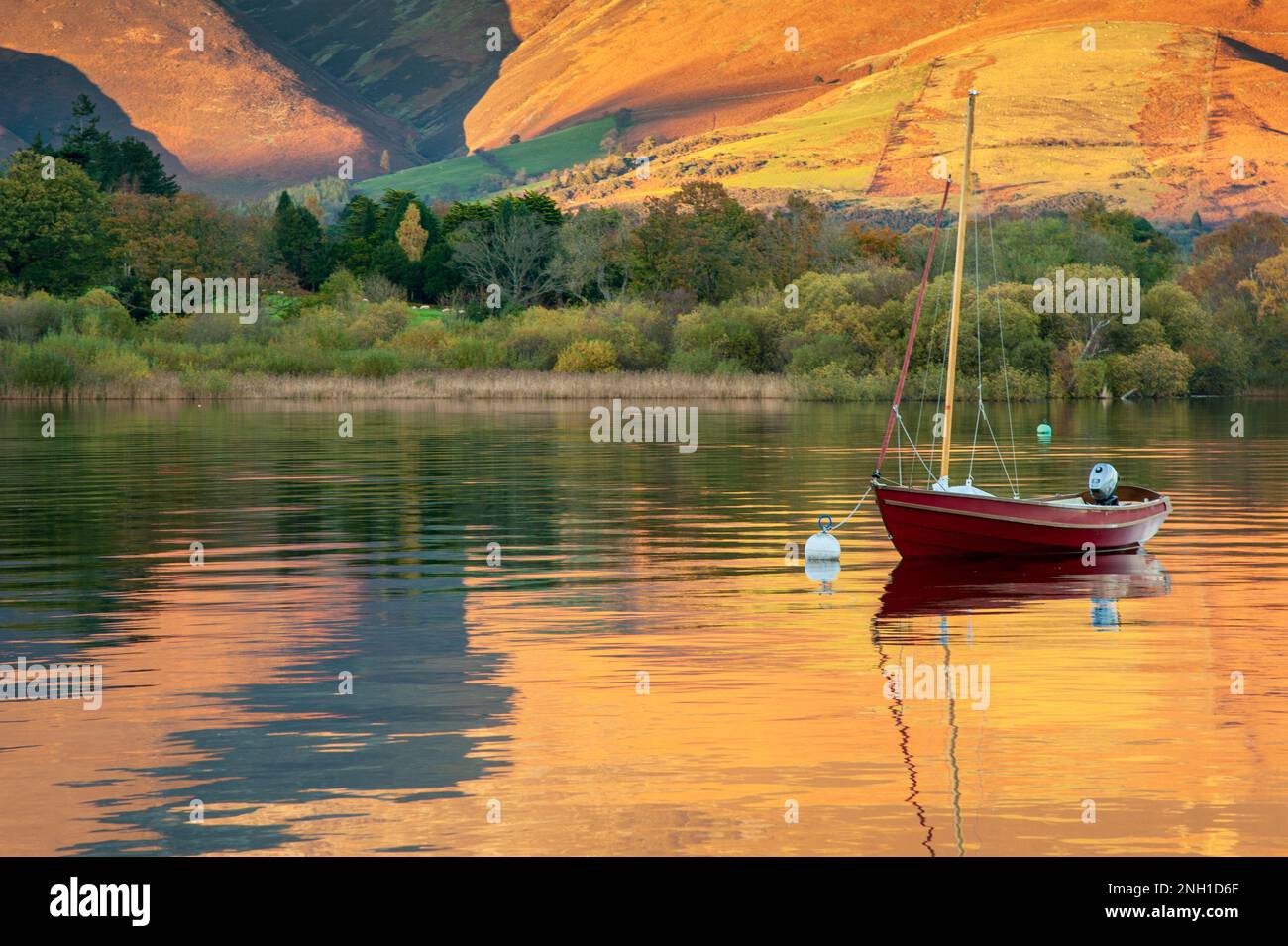 Rote Yacht in einem See mit Herbstfarben, die sich in der Stille widerspiegeln Stockfoto