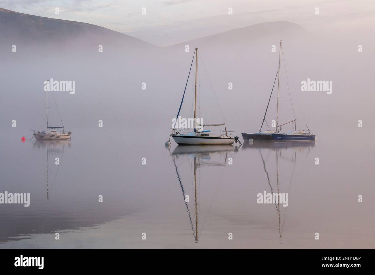 Yachten in einem nebligen Morgengrauen auf Derwentwater im Lake District Stockfoto