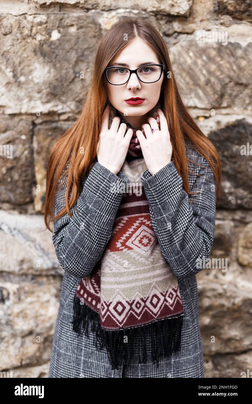 Junge Frau in Brille, die einen Mantel in einem Schal trägt Stockfoto