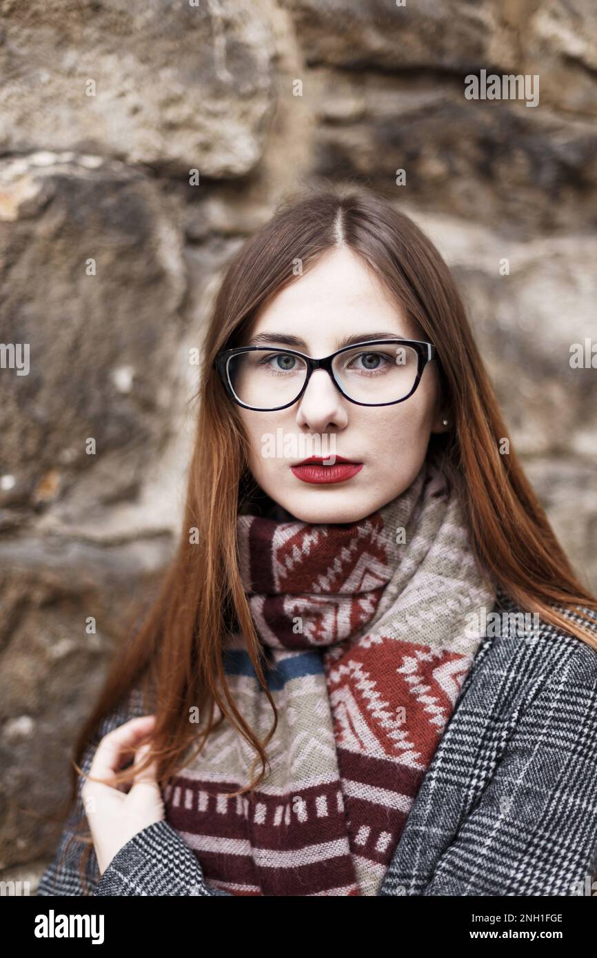 Junge Frau in Brille, die einen Mantel in einem Schal trägt Stockfoto