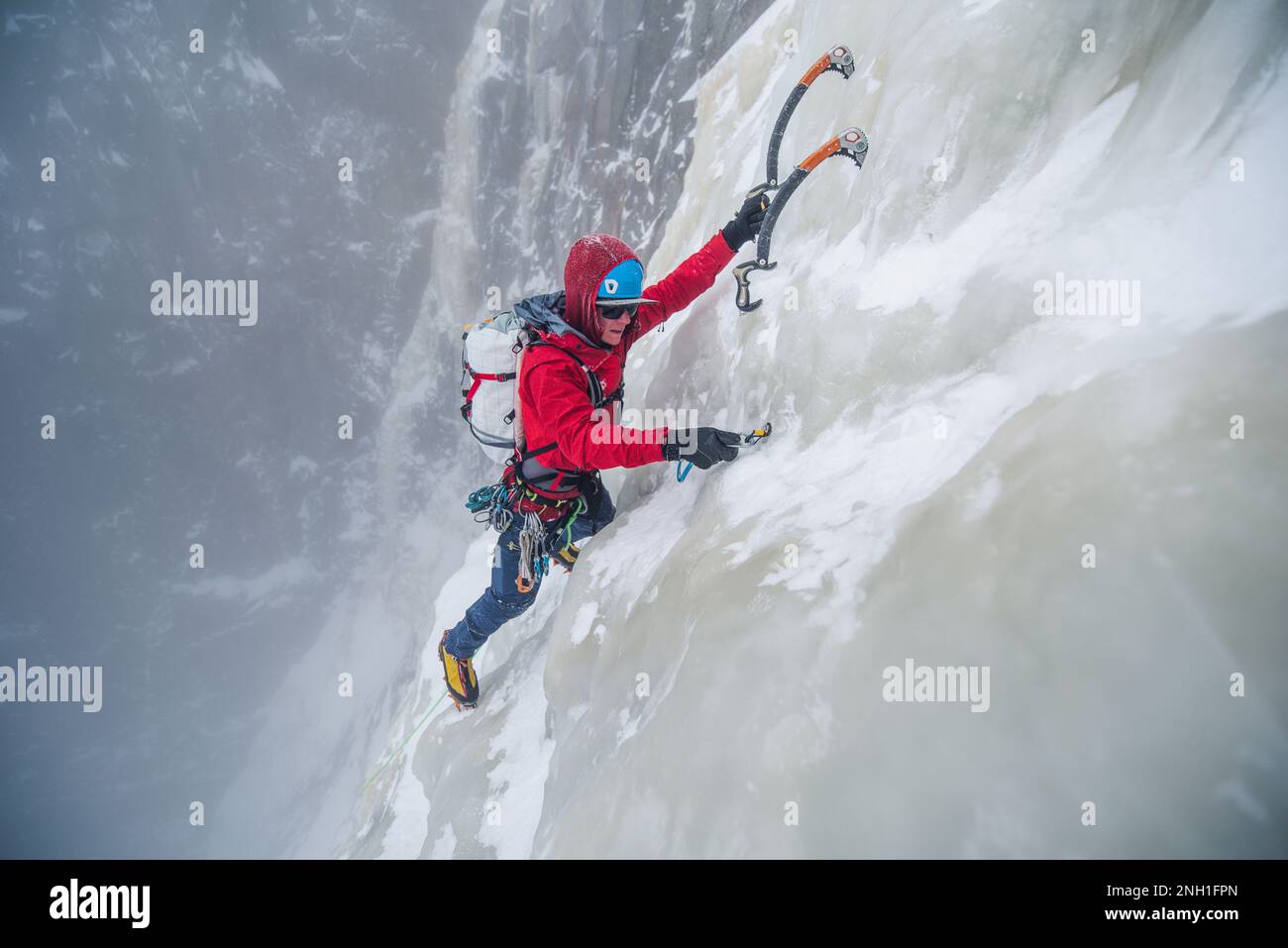 Eiskletterer, der beim Klettern die Eisschraube eindreht Stockfoto