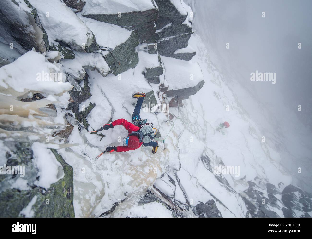 Eiskletterer, die einen steilen Abschnitt von Felsen und Eis besteigen Stockfoto
