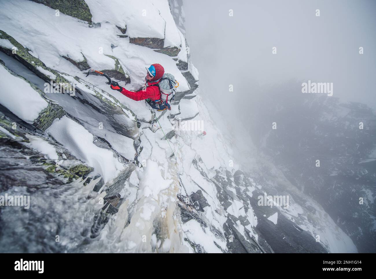 Eiskletterer, die einen steilen Abschnitt von Felsen und Eis besteigen Stockfoto