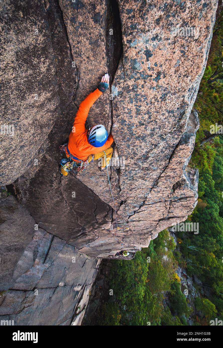 Ein Mann klettert auf die Felswand mit einem Hinterbliebenen Stockfoto