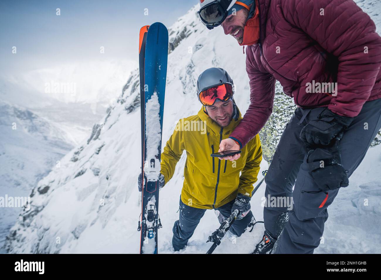Zwei Skifahrer, die sich Aufnahmen auf einem Handy ansehen Stockfoto