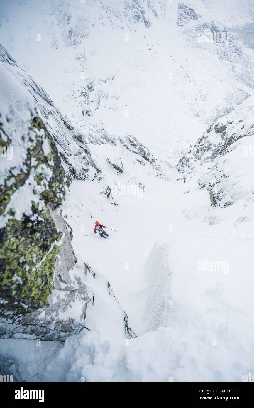 Skifahrer, die in einer Schlucht mit umliegenden Felswänden fahren Stockfoto