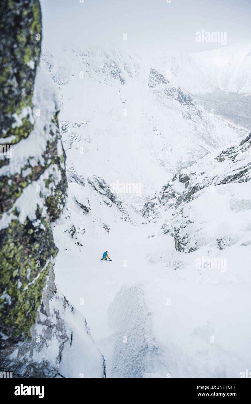 Skifahrer, die in einer Schlucht mit umliegenden Felswänden fahren Stockfoto