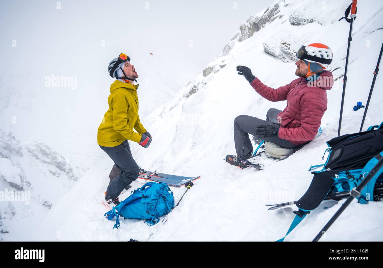 Skifahrer, die sich einen Snack auf einer Skipiste im Hinterland teilen Stockfoto