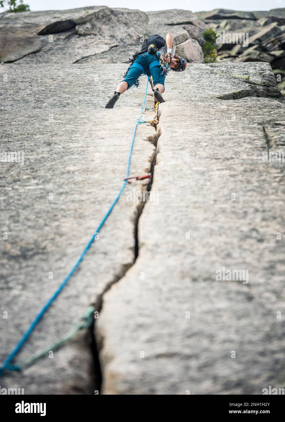 Ein Mann klettert auf einen festen Riss an der Klippe Stockfoto