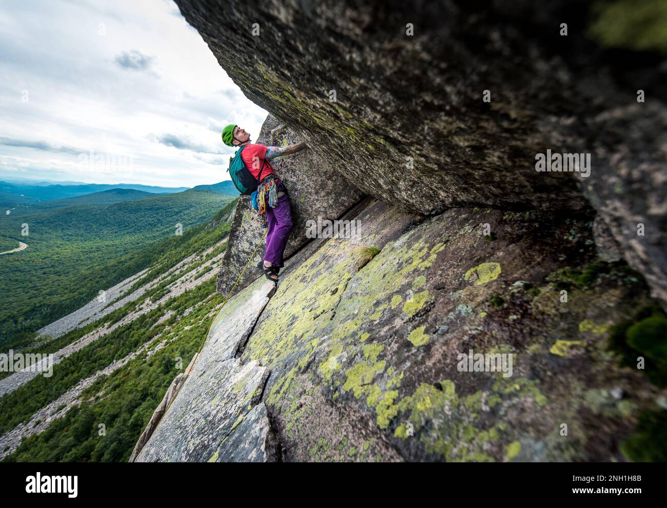 Felskletterer inspiziert nächsten Schritt auf Bergklippen Stockfoto