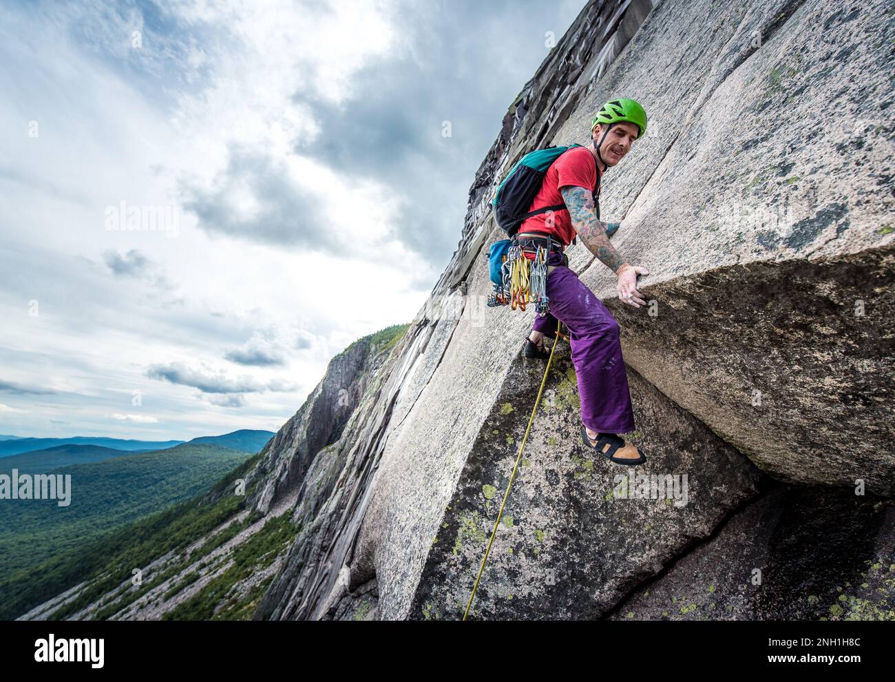 Ein Mann mit Tattoos, der steile Felswände hochklettert Stockfoto