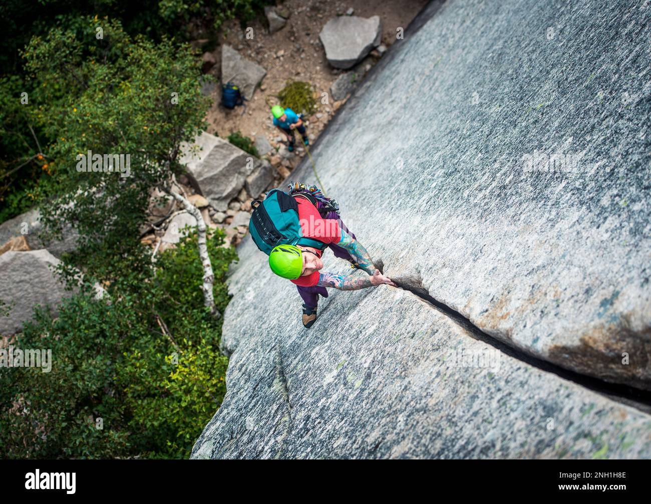 Ein Mann mit Tattoos klettert auf einen Riss an einer Felswand Stockfoto