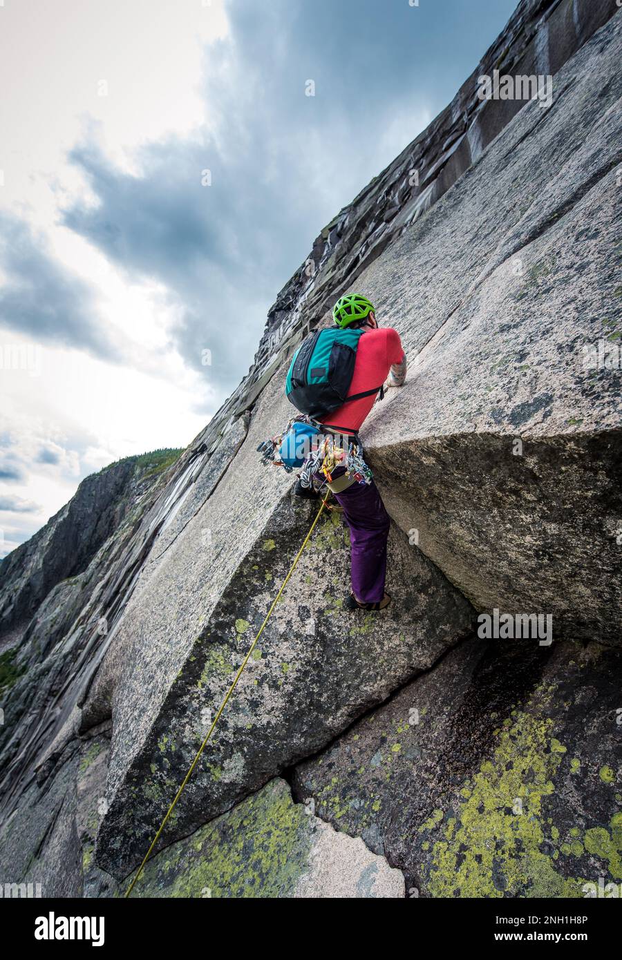 Mann mit Tattoos klettert steile Felswand hoch Stockfoto