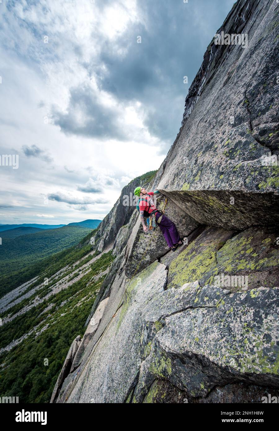 Ein Mann mit Tattoos, der den nächsten Schritt beim Klettern inspiziert Stockfoto