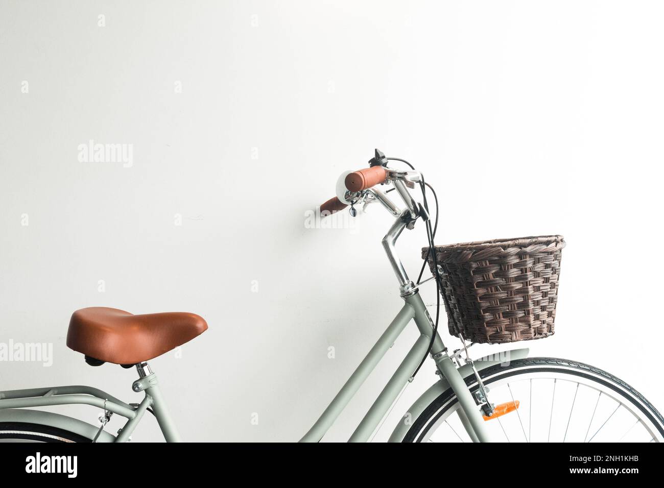 Altes grünes Fahrrad mit braunem Korb auf weißem Hintergrund Stockfoto