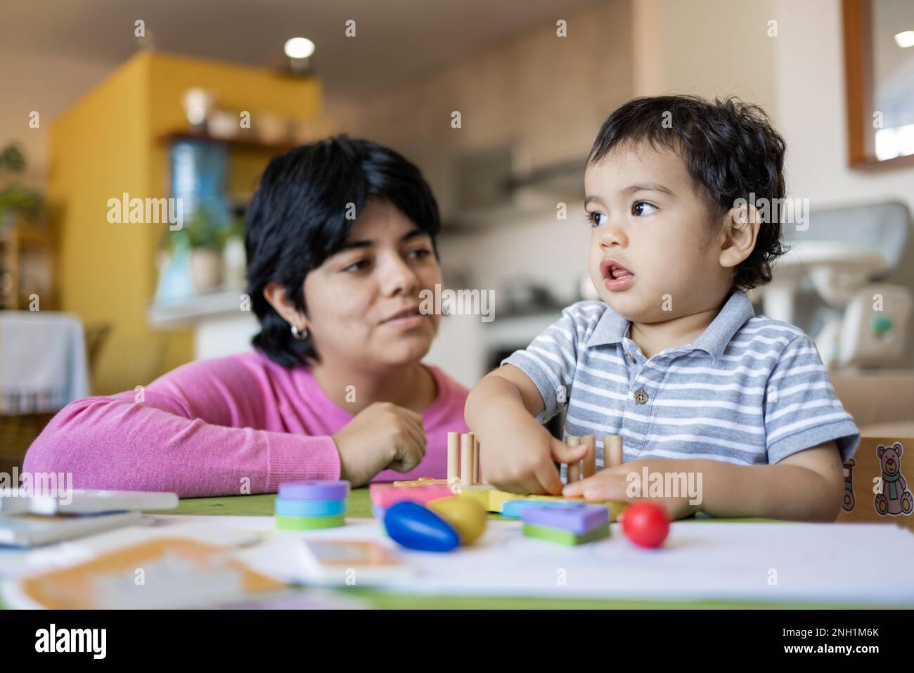 Lateinische Mutter und kleiner Sohn spielen mit Logikspielzeug aus Holz. Stockfoto