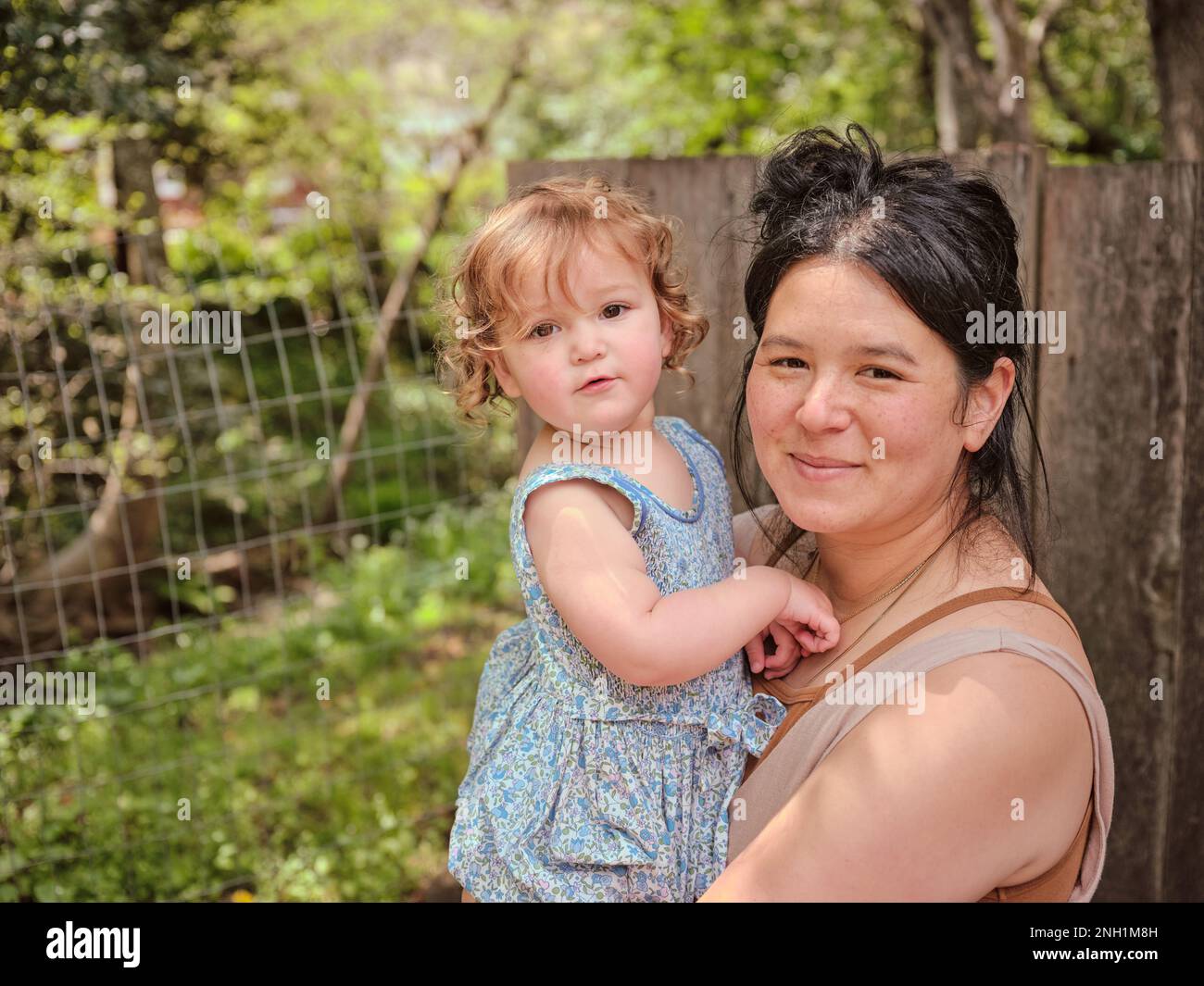 Mom hält die Tochter fest und schaut in den Garten Stockfoto