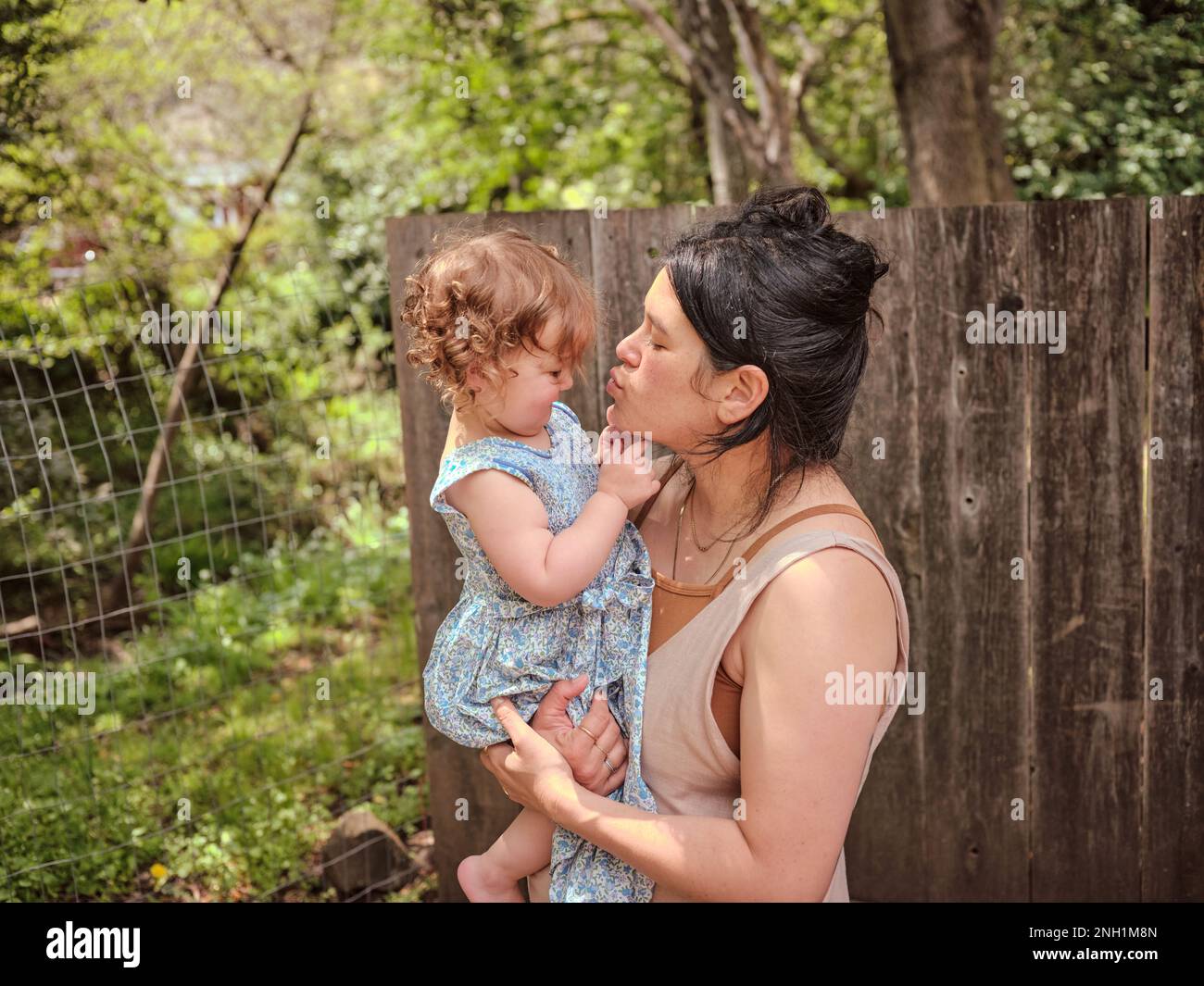 Mutter und Tochter umarmen und zeigen Zuneigung in einem eingezäunten Garten Stockfoto
