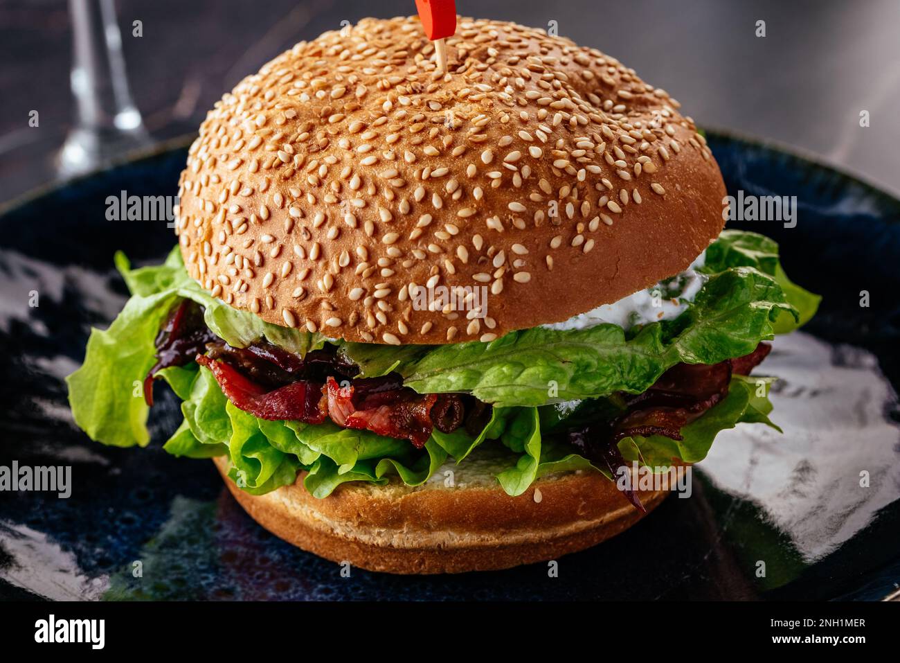 Saftiger Burger auf einem Teller auf dunklem Hintergrund Stockfoto