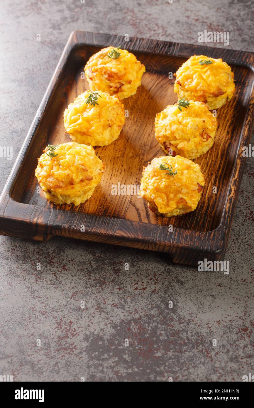 Frisch gebackene Muffins mit Kräutern, Kartoffeln, Speck und Käse auf Holzbrettern auf dem Tisch. Vertikal Stockfoto