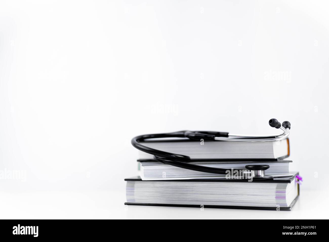 Stethoskop, das sich mehrere Medizinbücher anhört. Weißer Hintergrund mit Kopierbereich. Isoliertes Lernkonzept Medizin, Kardiologie, Gesundheit Stockfoto