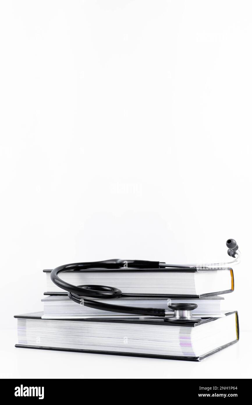Stethoskop, das sich mehrere Medizinbücher anhört. Weißer Hintergrund mit Kopierbereich. Isoliertes Lernkonzept Medizin, Kardiologie, Gesundheit Stockfoto