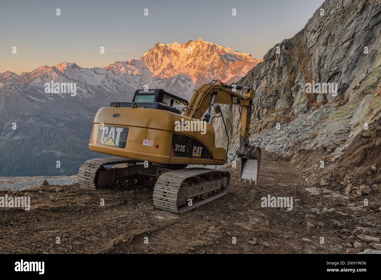 Arbeiten Sie in großen Höhen in den Bergen. Caterpillar-Hydraulikbagger baut eine unbefestigte Straße. Kat Stockfoto