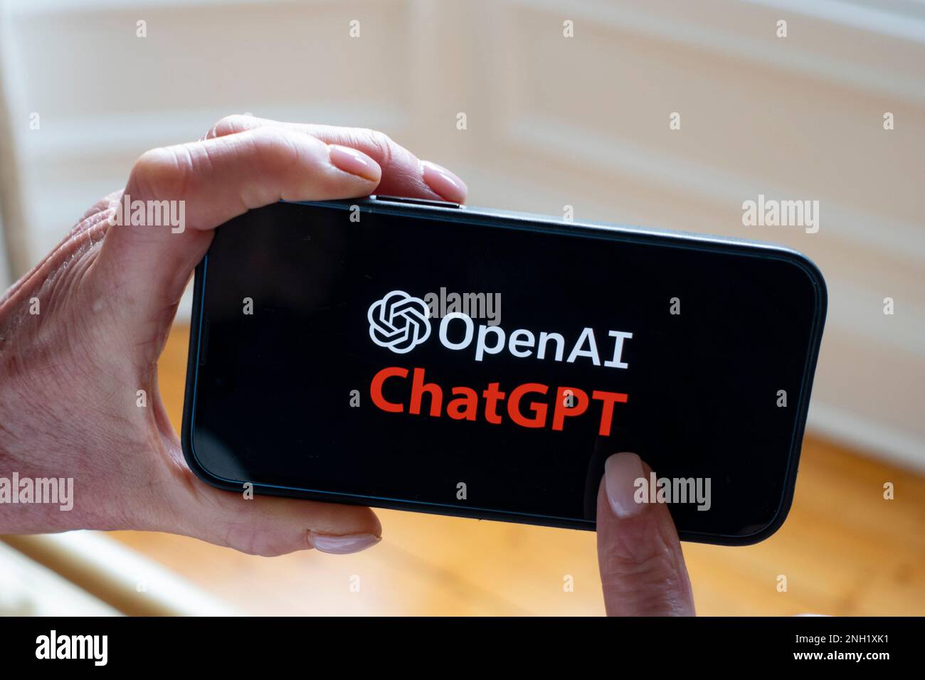 Person hat ein Mobiltelefon, auf dem das Microsoft ChatGPT OpenAI Chatbot-Logo angezeigt wird Stockfoto