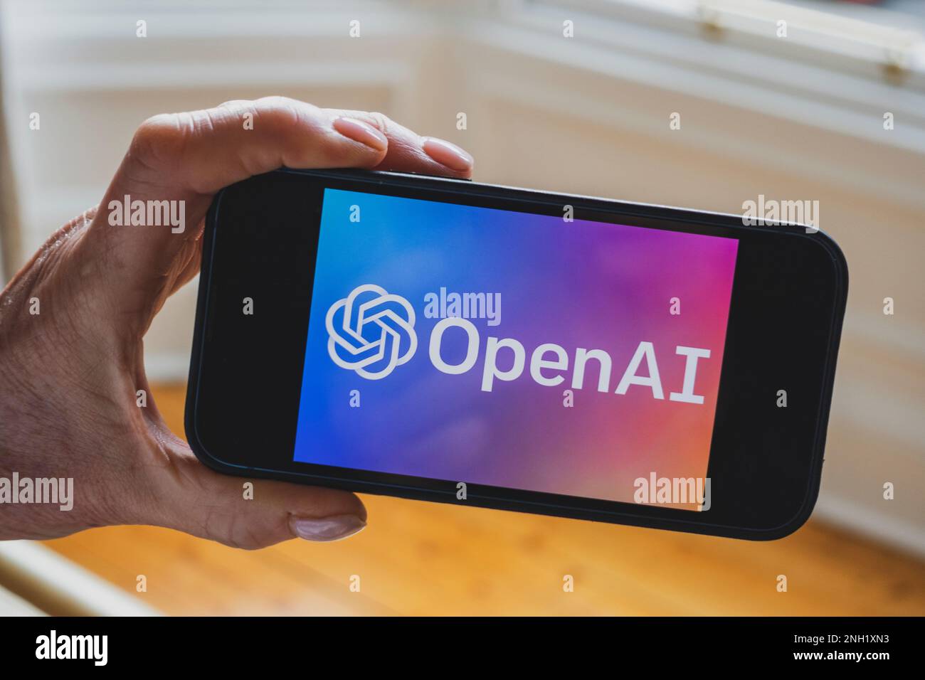 Person hat ein Mobiltelefon, auf dem das Microsoft ChatGPT OpenAI Chatbot-Logo angezeigt wird Stockfoto